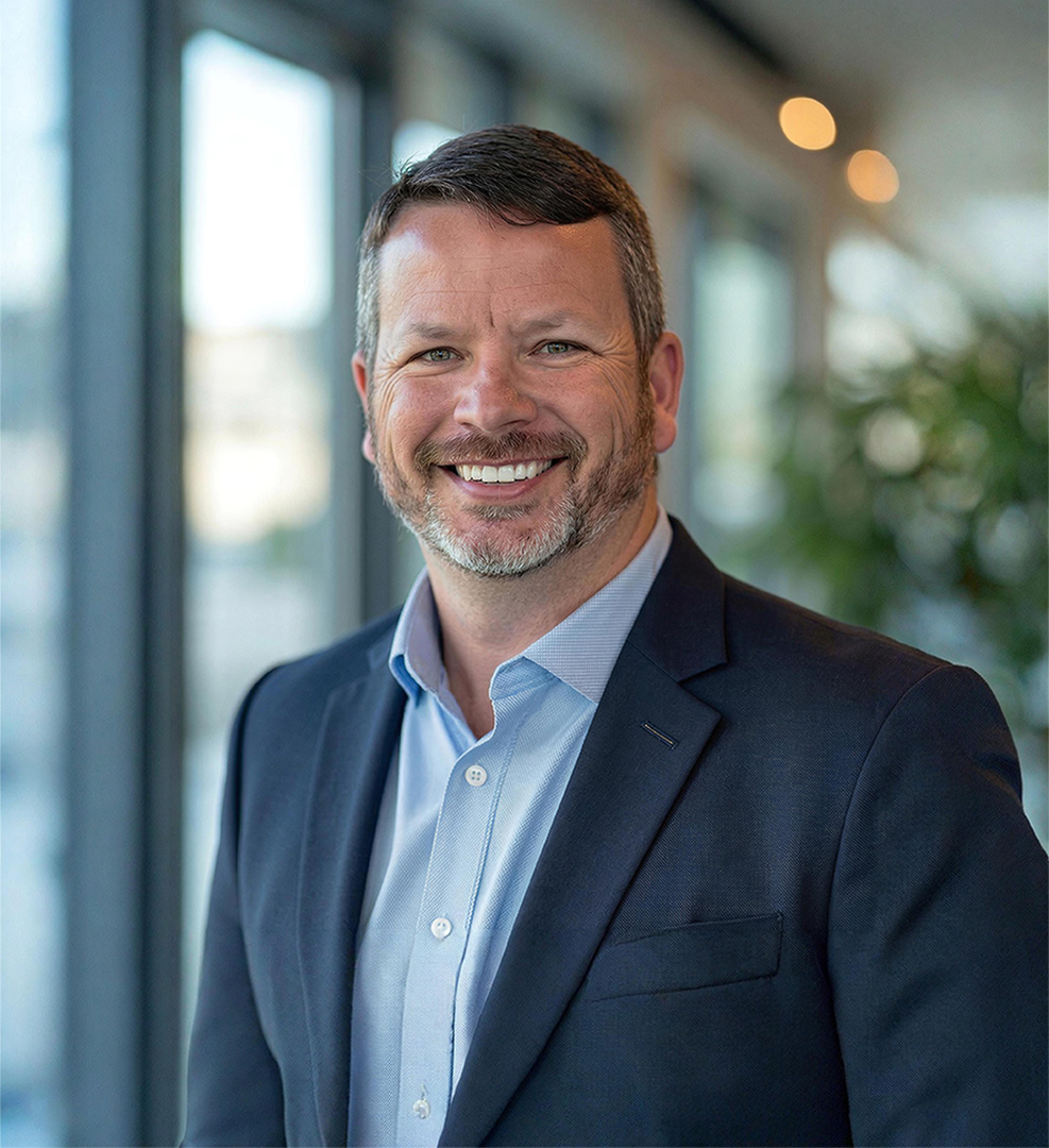 CJ Thompson in a suit jacket and a blue collared shirt 
